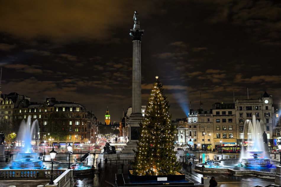 Albero di Natale illuminato e fontane accese a Trafalgar Square di notte, ai piedi della colonna di Nelson